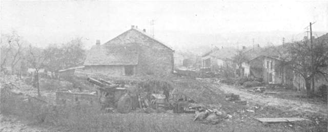 A 155 mm Howitzer set up in the backyard of a German town still occupied by German civilians and still under German artillery fire.