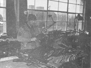 A German arms plant captured in Zella-mellis, Germany. The soldier is examining a new type gun never issued due to capture.